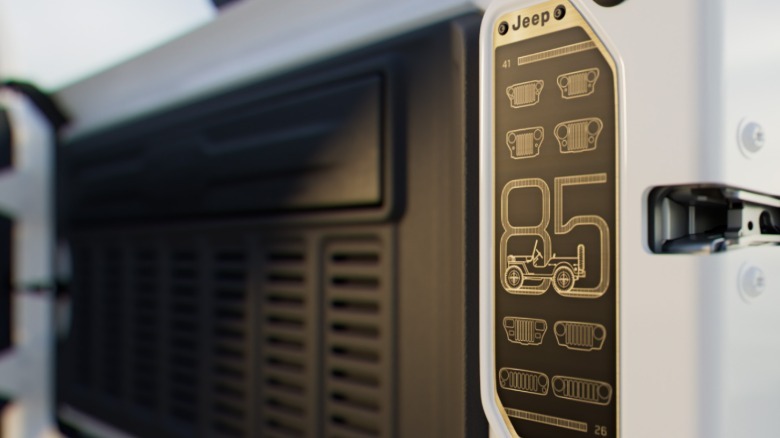 A close-up of an 85th anniversary badge on the tailgate of a white Wrangler